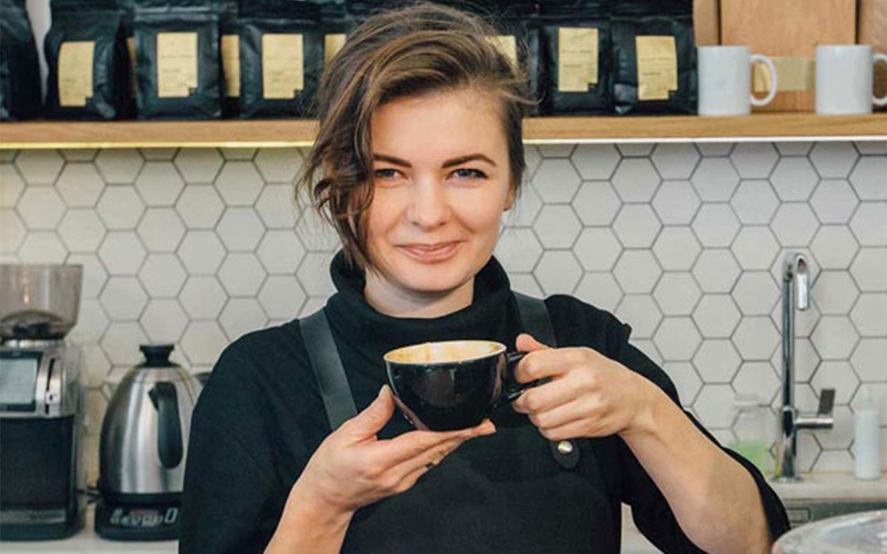 Woman holding a cup of coffee, smiling.