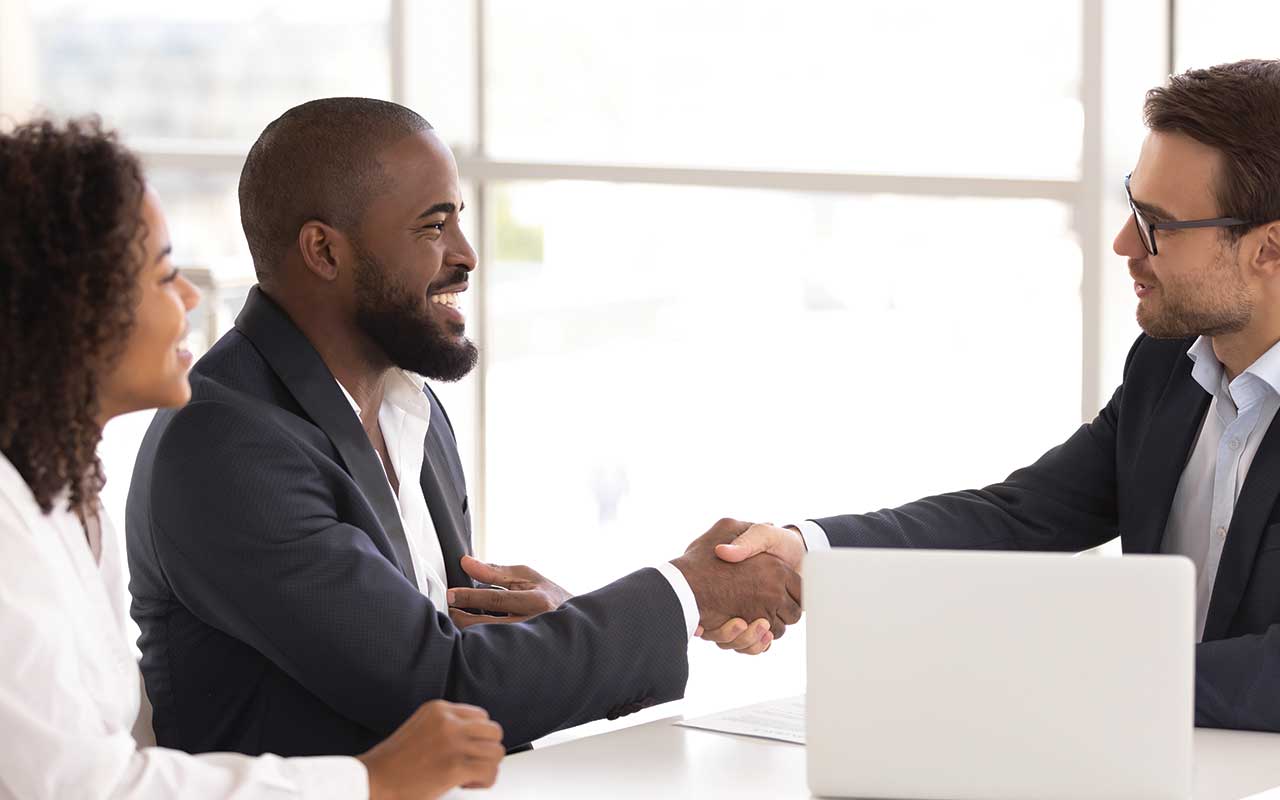 man shaking hands over a laptop