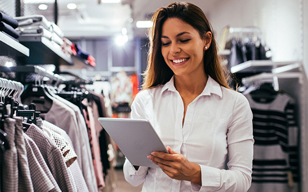 Woman in a clothing store holding a tablet.