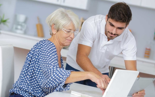 A woman pointing at a laptop while a man holds a tablet and points at the laptop.