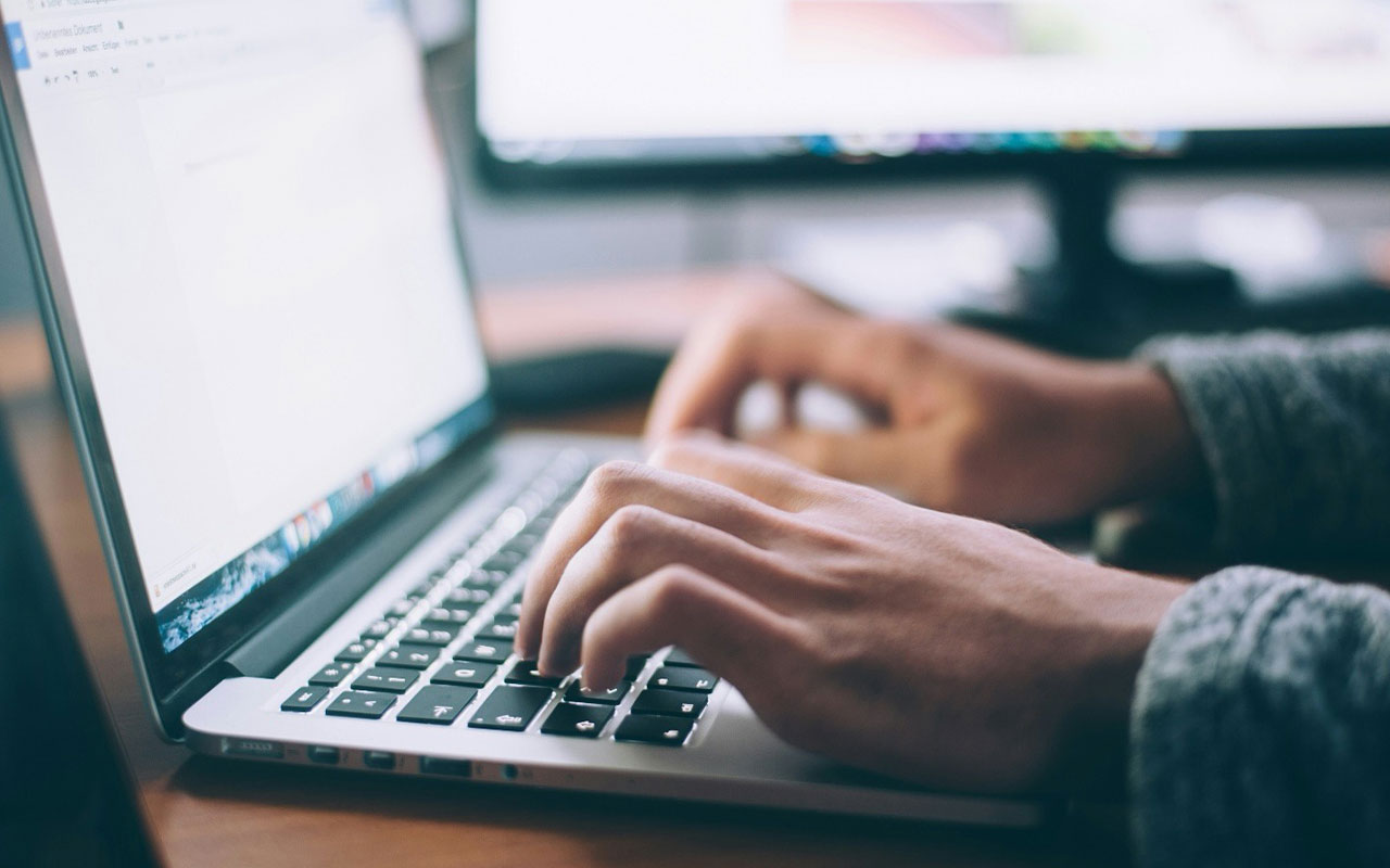 Hands resting on the keyboard of an open laptop.