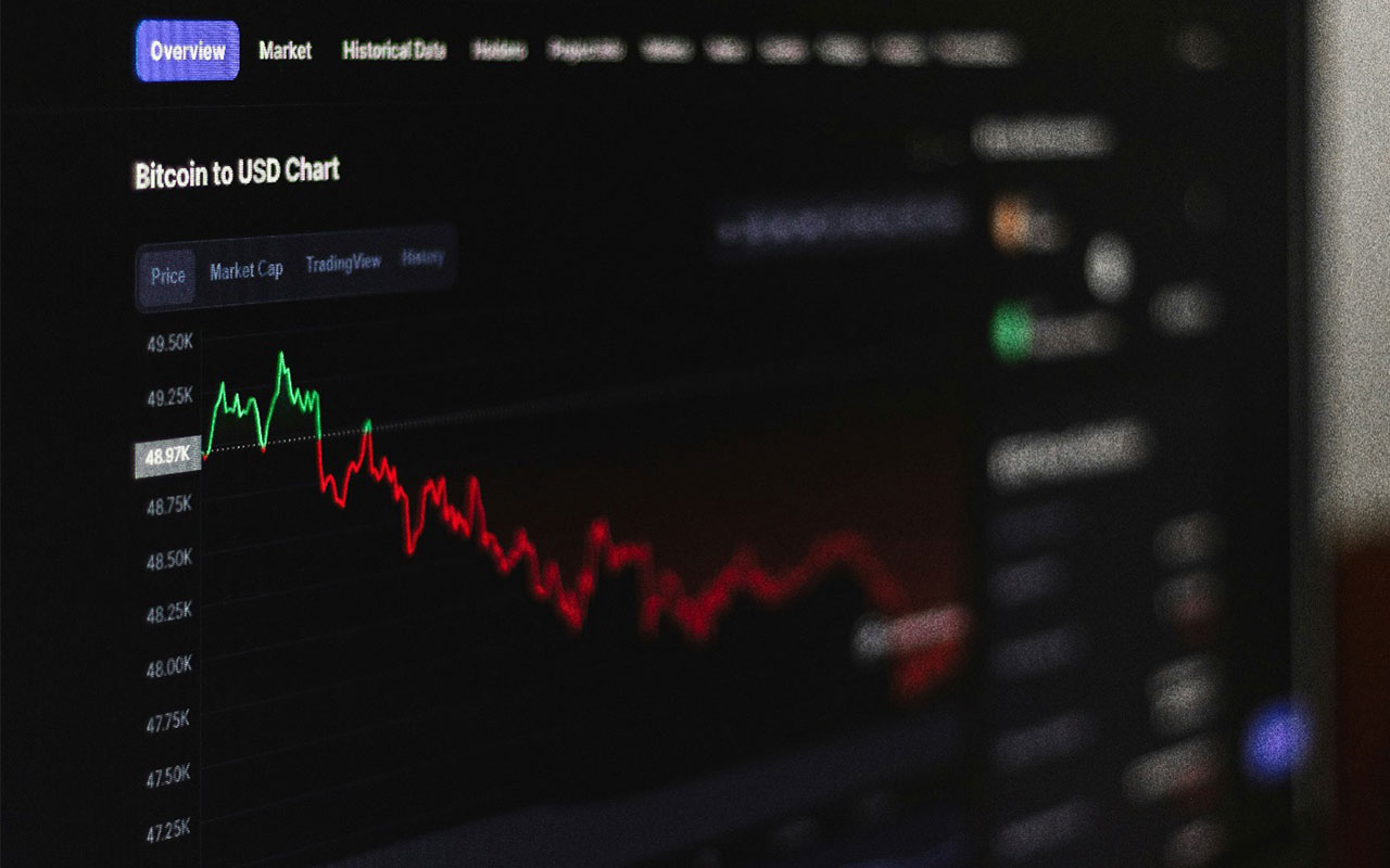 A computer screen with a Bitcoin chart going from green down to red.