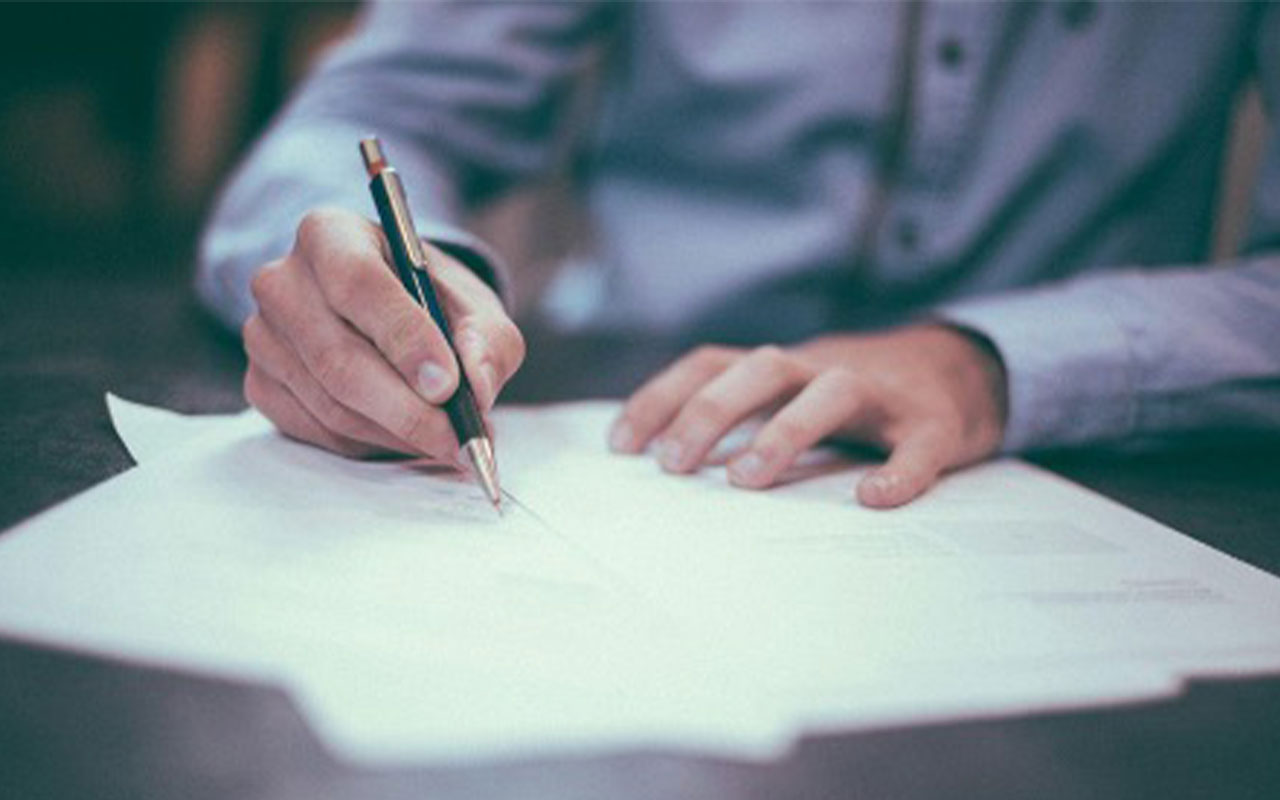A person holding a pen and signing papers.