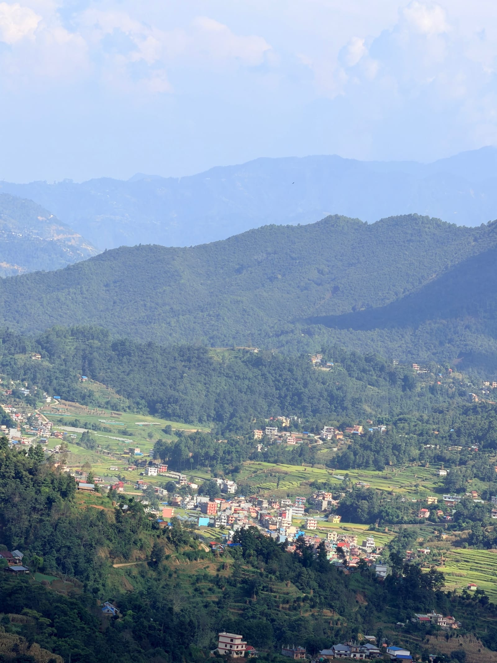Panoramic view of terraced farmland and village houses nestled in the green hills of Kavrepalanchok, Nepal