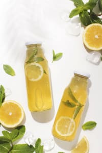 Erfrischungsgetränk mit Zitrone und Minze in Flaschen auf Eis