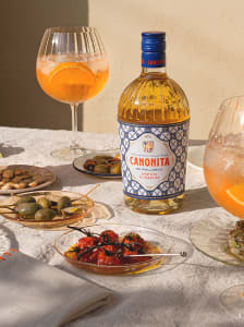 Eine Flasche Canonita-Orangenlikör mit zwei Gläsern und Antipasti.