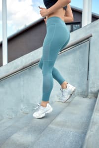 Frau in Sportkleidung rennt eine Treppe herunter