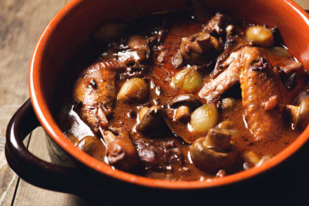 Coq au Vin mit Zwiebeln und Pilzen im Schmortopf