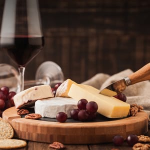 Käseplatte mit verschiedenen Sorten und einem Glas Rotwein.