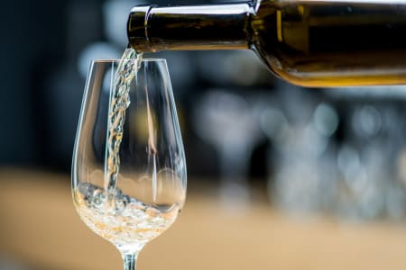 Weißwein wird in ein Glas eingeschenkt.