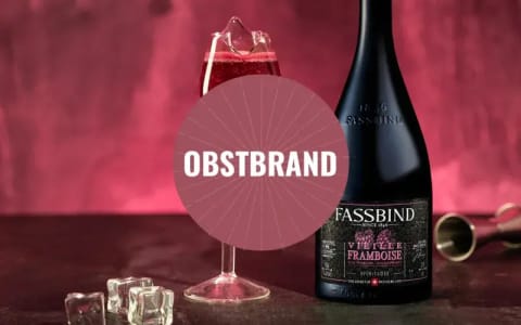 Eine Flasche Obstbrand der Marke Fassbind mit gefülltem Glas.