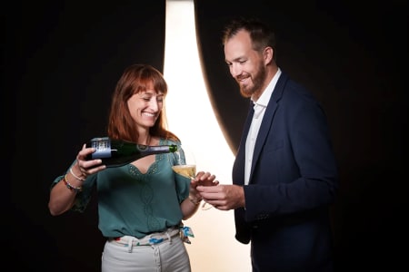 Eine Frau schenkt einem Mann ein Glas Charles Heidsieck Champagner ein.