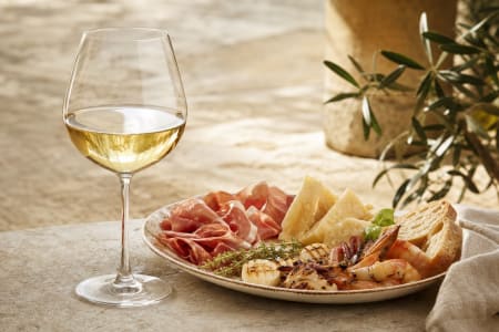 San-Daniele-Schinken, Montasio und gegrillte Meeresfrüchte, dazu ein Glas Chardonnay Weißwein.
