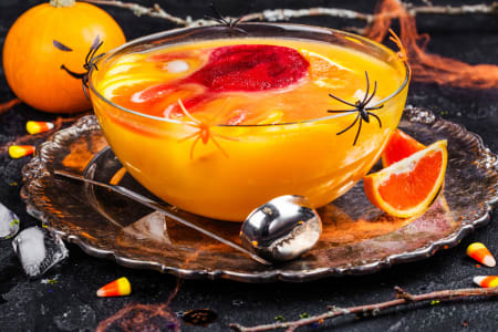 Orangene Bowle mit Kelle und Halloween-Dekoration.