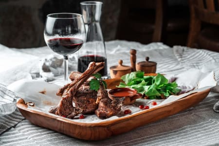 Conde Valdemar Crianza zu gegrillten Lammkoteletts mit Blattsalat und Dip, serviert mit Rotwein auf rustikal gedecktem Tisch.