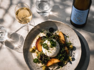 Gebratenes Lachsfilet mit Gemüse und Zitrone, serviert mit einem Glas Riesling Weißwein