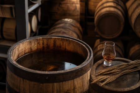 Ein geöffnetes Whiskey-Fass mit Whiskey-Glas und Roggen.