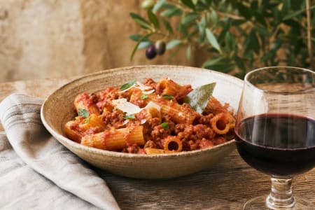 Ein Glas Terre Siciliane Merlot Rotwein zu Pasta mit Tomaten-Ragù.