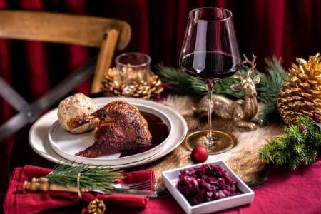 Weihnachtsessen mit Gans, Knödeln, Rotkohl und einem Glas Rotwein.