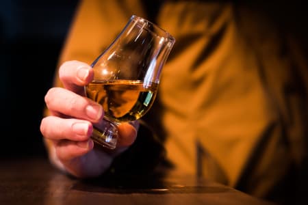 Ein Whiskyglas wird bei einer Verkostung geneigt.