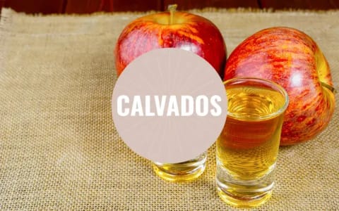 Zwei Schnapsgläser mit Calvados und zwei Äpfel.