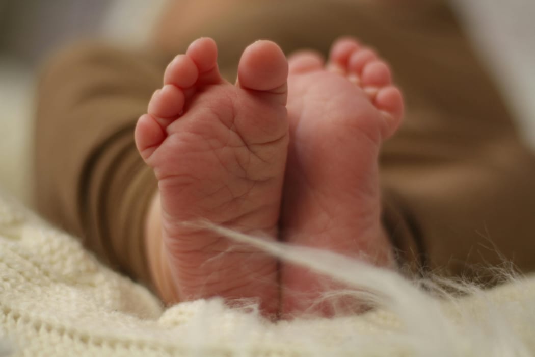 Nahaufnahme von Babyfüßen in weichem Strickdeckenstoff