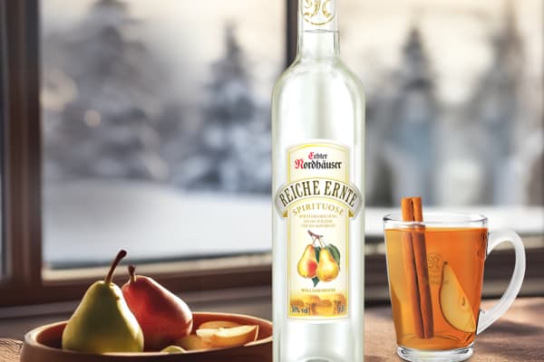 Reiche Ernte Williamsbirne und Hot Willi Cocktail im Glas vor winterlicher Landschaft