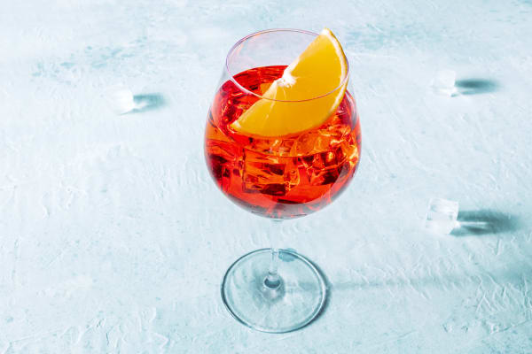 Ein Glas Carpano Spritz mit Orangenscheibe.