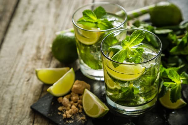 Glas Virgin Mojito als alkoholfreier Cocktail, mit frischer Minze, Limettenscheiben und Crushed Ice, serviert auf einem Tisch.