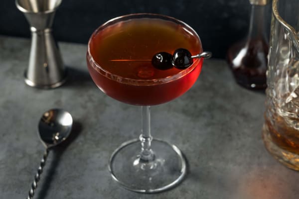 Roter Manhattan-Cocktail mit Cocktailkirsche garniert.
