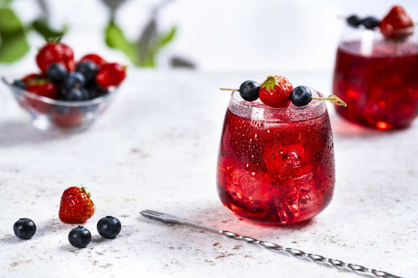Mocktail Virgin Berry im Glas auf einem Tisch, dekoriert mit frischen Beeren.
