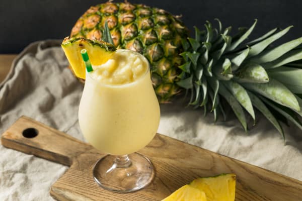 Mocktail Virgin Colada im Glas auf einem Tisch, dekoriert mit frischer Ananas.