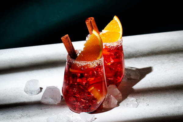 Zwei Winter-Canonita-Spritz-Cocktails, garniert mit Zimtstange und Orangenscheibe.