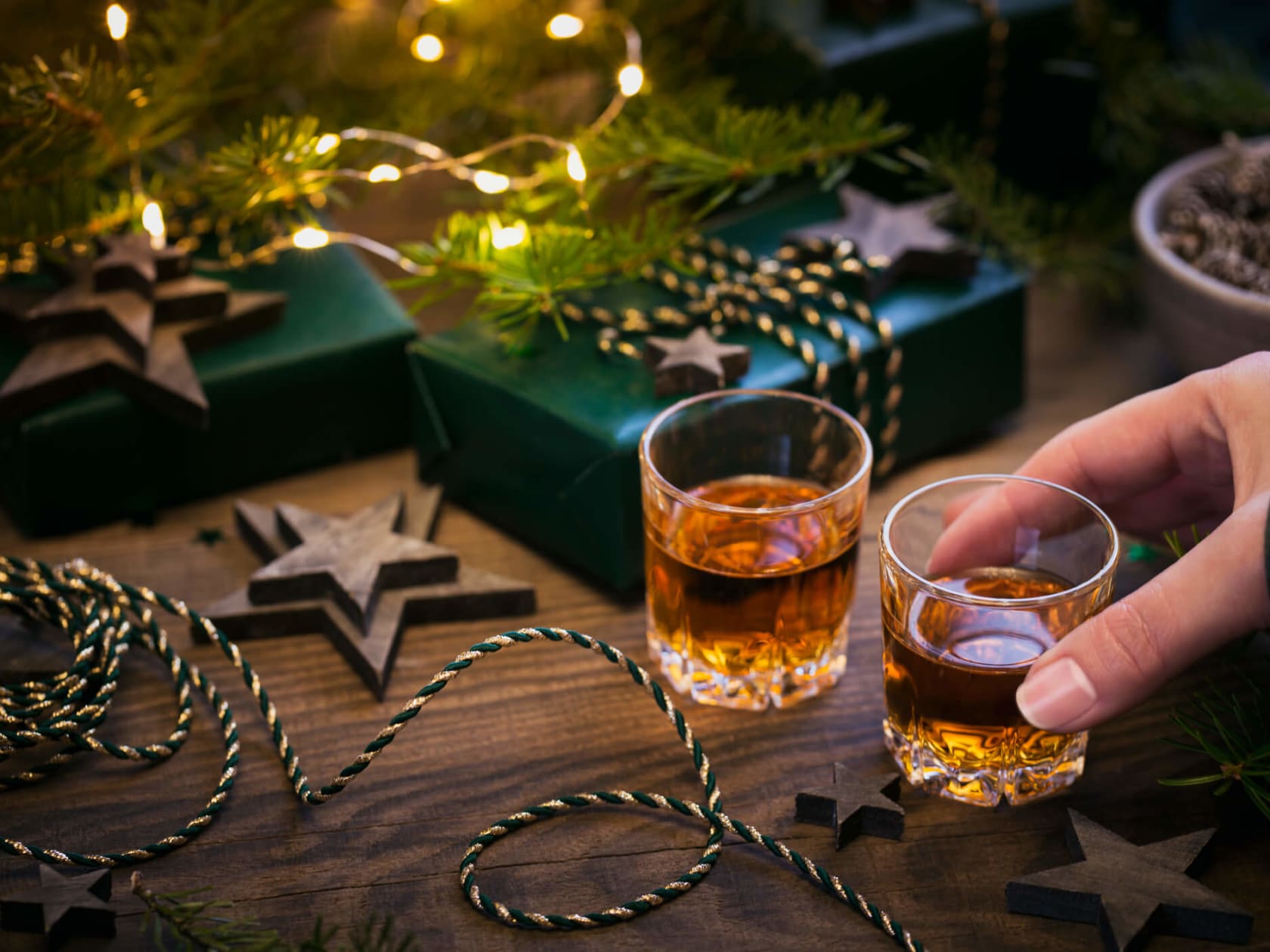 Zwei Whisky-Gläser und Geschenke mit weihnachtlicher Dekoration.