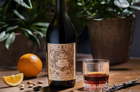Eine Flasche Antica Formula Wermut mit Orange und Glas.