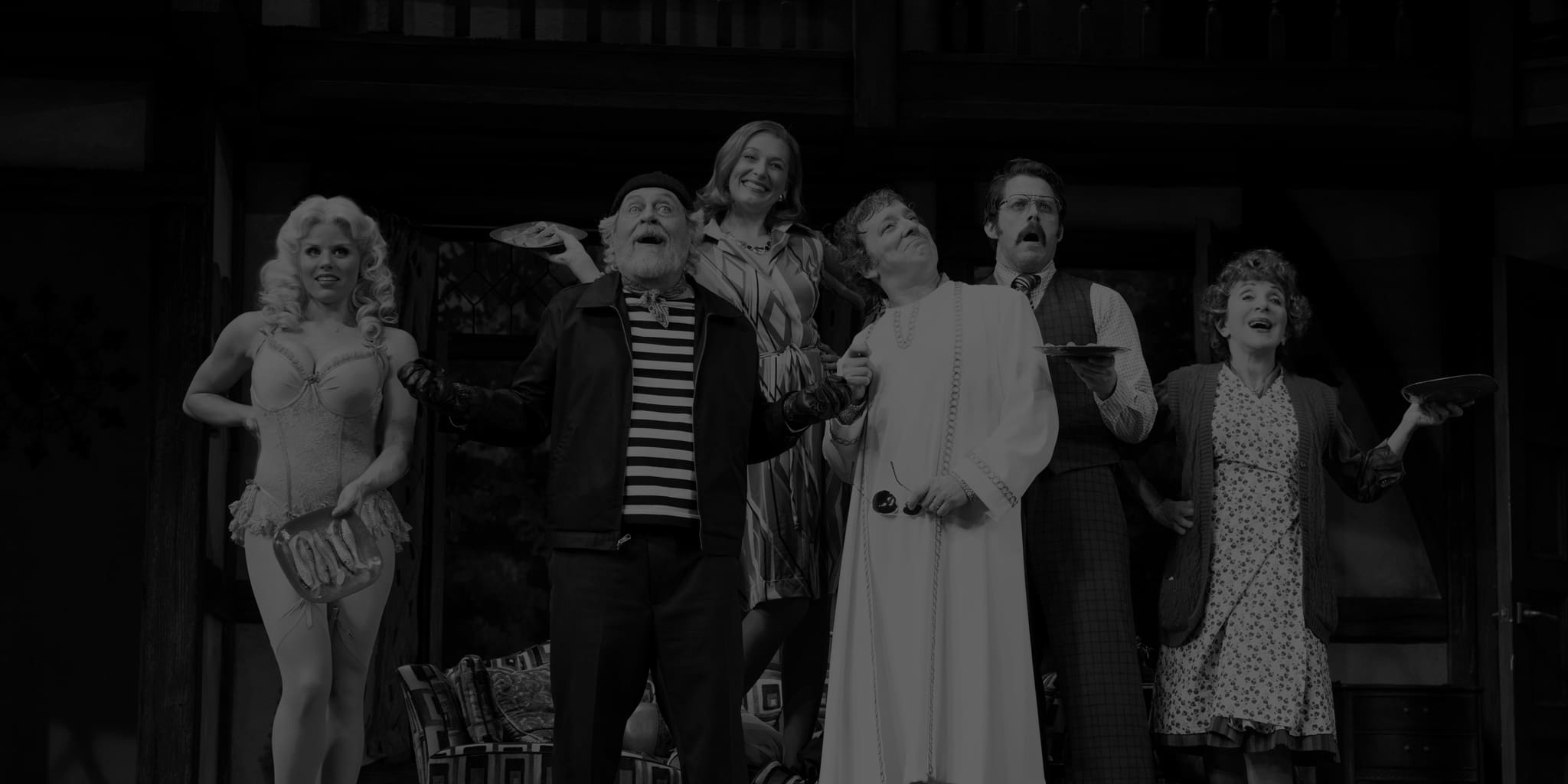 Production photo from NOISES OFF. An eclectic group of actors on stage all hold red trays with sardines on them.