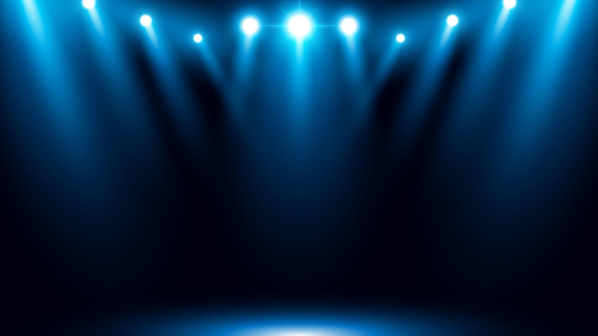 Blue lights shine into the blackness of an empty stage.