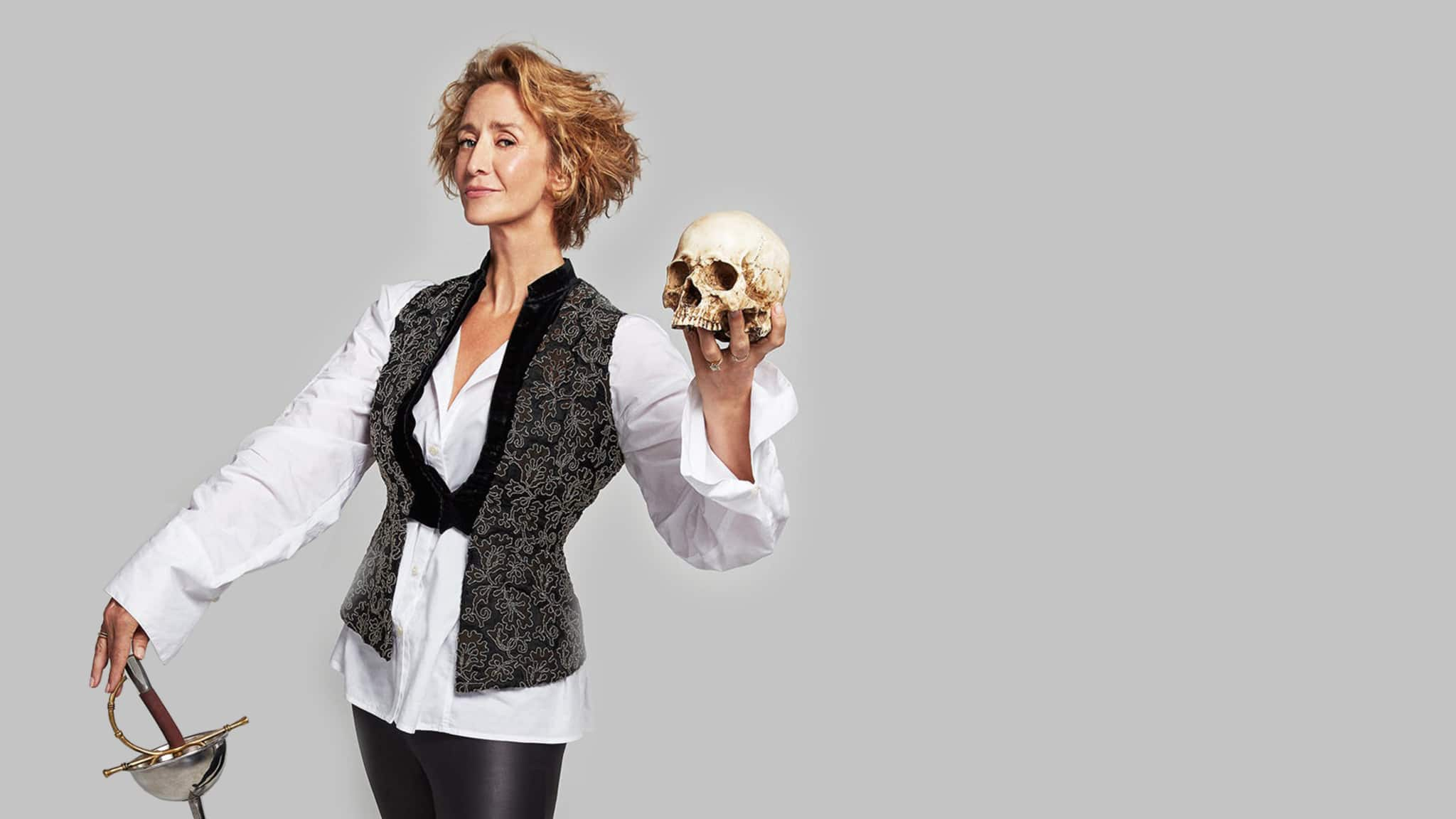 Artwork for Bernhardt/Hamlet. A woman with short layered blonde hair stands poised in Shakespearean clothing and holds a skull in one hand and a thin sword in the other.