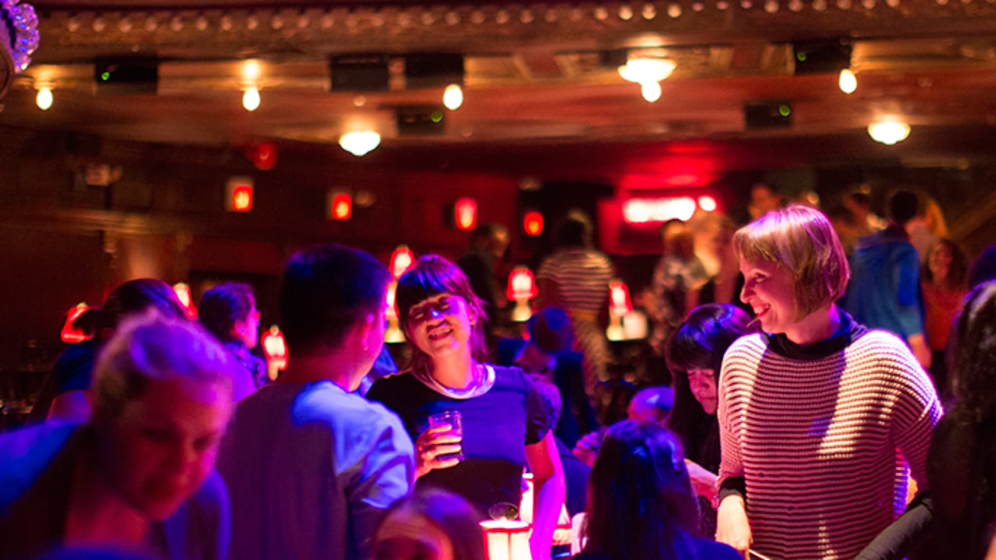 A group of people at a casual party talk and hold drinks.