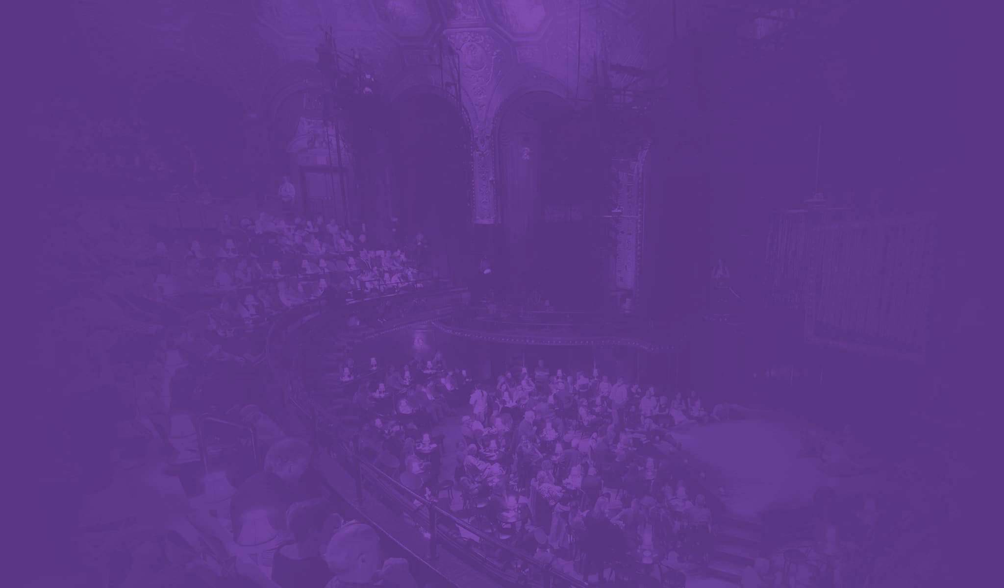 A crowded audience at the theater with a purple overlay.