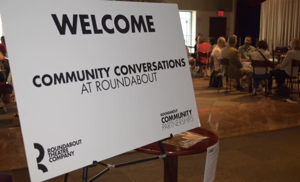 A white poster board in the Todd Haimes Theatre penthouse lobby reads, WELCOME COMMUNITY CONVERSATIONS AT ROUNDABOUT.