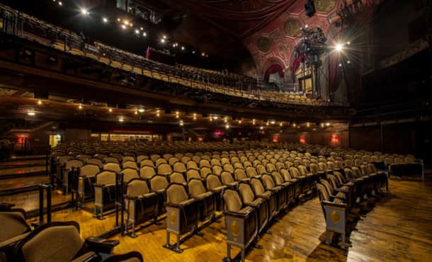 The empty house of Studio 54. The floor of the orchestra section is wooden. Elaborate gold moldings are on the red walls and ceilings.