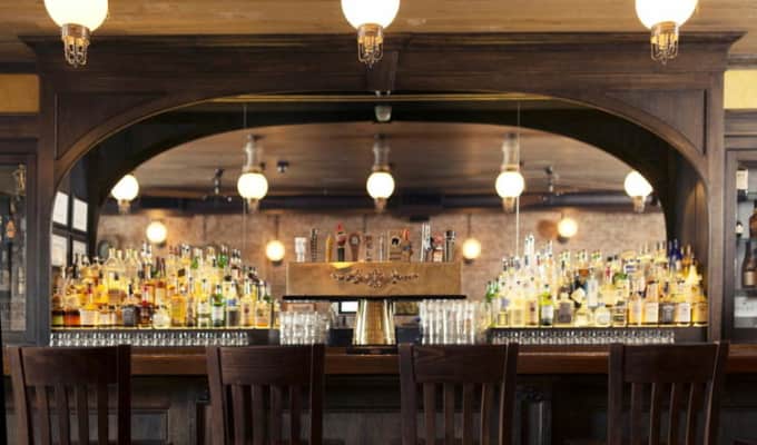 A large bar with an arch over it. Fancy lighting hangs over and illuminates the bottles of alcohol.
