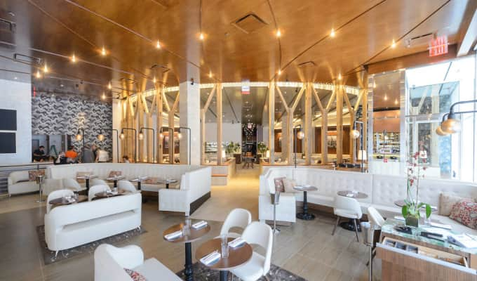 A fancy white lounge area with white furniture with sparkly and natural lighting.