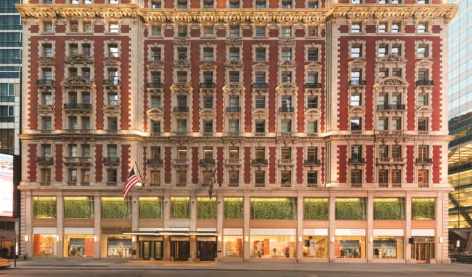 Exterior view of The Knickerbocker Hotel, a red and gold corner building with rows and rows of windows.