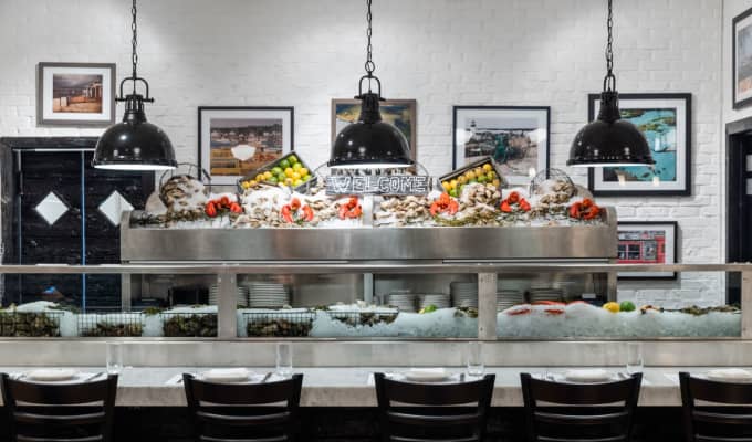 An oyster bar with low hanging lamps overtop.