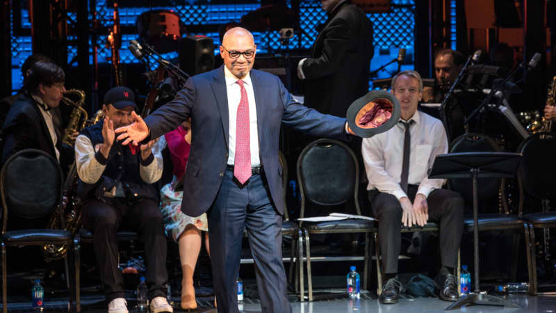 Reggie Jackson takes his bow on stage. He wears a suit with a red tie.