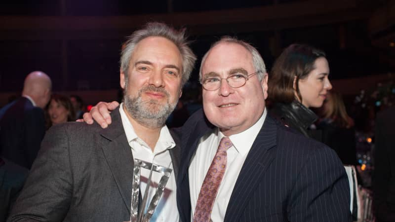 Todd Haimes and a friend wear suits and smile while posing for a photo together.