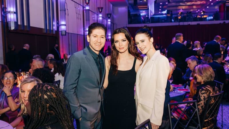 Three people pose for a picture amidst the tables of the Ziegfeld ballroom.