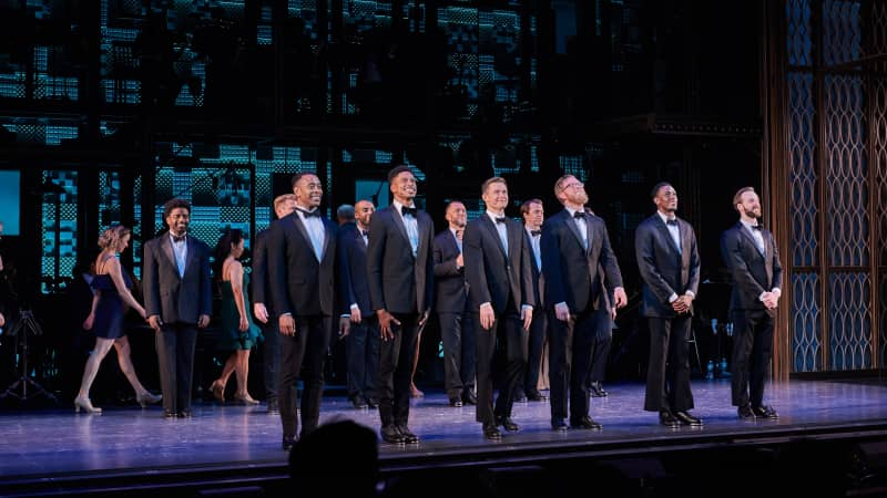 The cast of MY ONE AND ONLY at curtain call. A line of men in tuxedos take their bow.